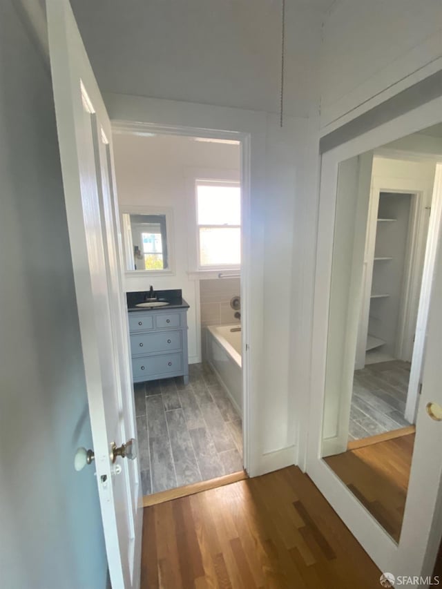 bathroom featuring a tub, vanity, and wood-type flooring