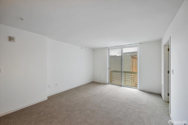 unfurnished room with light colored carpet and baseboards