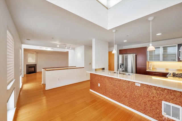 kitchen with light wood finished floors, visible vents, appliances with stainless steel finishes, decorative light fixtures, and light countertops