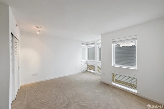 unfurnished room featuring light carpet and baseboards