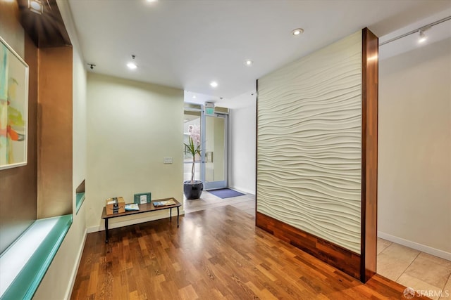 hall featuring baseboards, light wood-type flooring, and recessed lighting