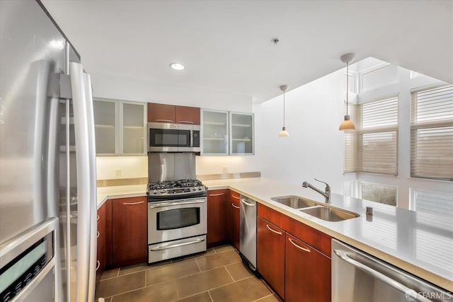 kitchen with decorative light fixtures, light countertops, appliances with stainless steel finishes, glass insert cabinets, and a sink