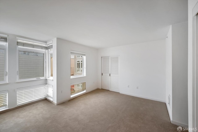 carpeted spare room featuring baseboards