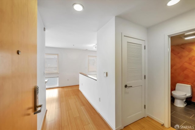 corridor with baseboards and light wood-style floors