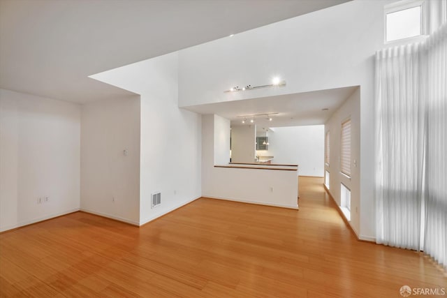 interior space with baseboards, track lighting, visible vents, and light wood-style floors