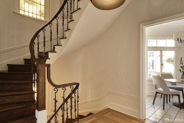 staircase featuring an inviting chandelier and tile patterned flooring