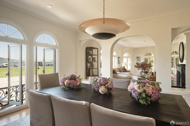 dining space featuring wood-type flooring, crown molding, and a wealth of natural light