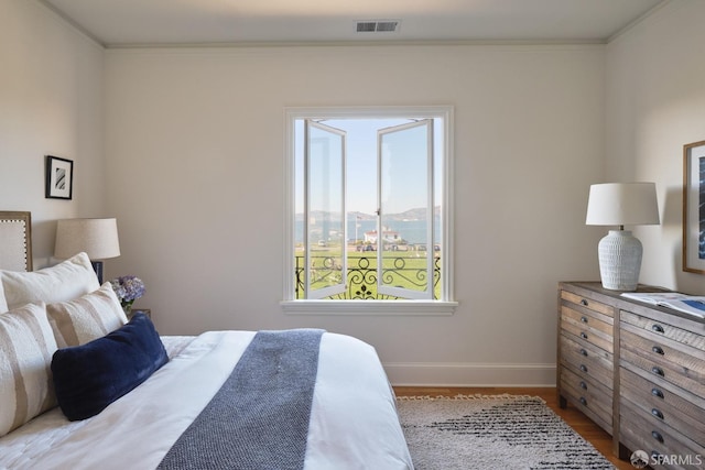 bedroom with light wood-type flooring, ornamental molding, and a mountain view