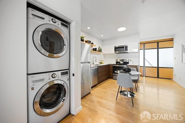 laundry room with stacked washer and dryer, sink, and light hardwood / wood-style floors