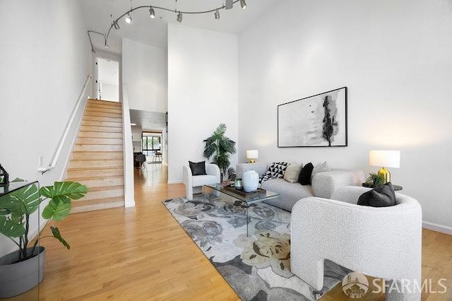 living room featuring a towering ceiling, wood-type flooring, and rail lighting