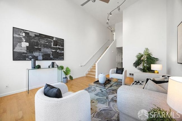 living room featuring hardwood / wood-style flooring, high vaulted ceiling, rail lighting, and ceiling fan