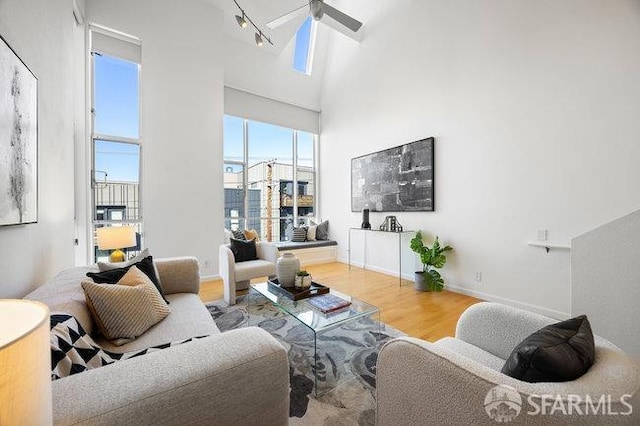 living room featuring hardwood / wood-style flooring, ceiling fan, and a high ceiling