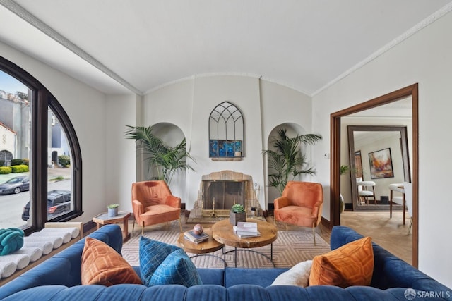 living area featuring baseboards, wood finished floors, lofted ceiling, and a fireplace with raised hearth