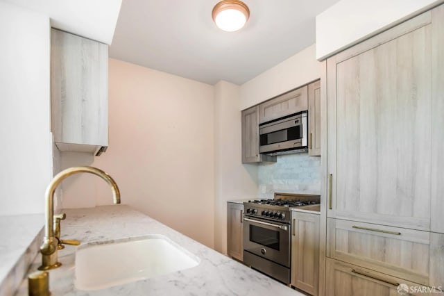 kitchen with light stone countertops, tasteful backsplash, appliances with stainless steel finishes, and a sink