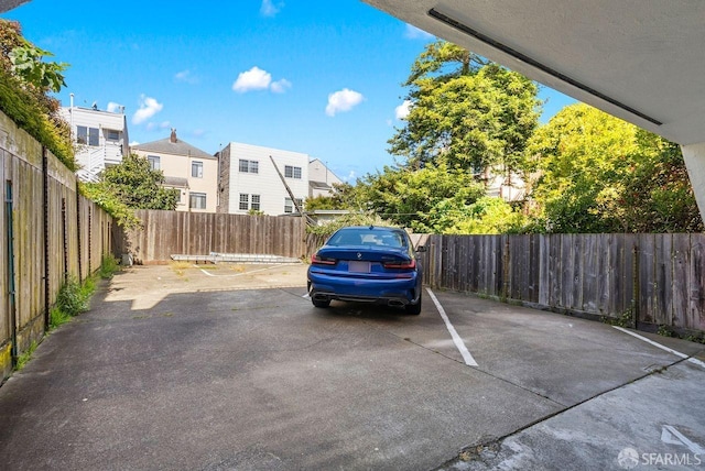 uncovered parking lot featuring a fenced backyard and a residential view