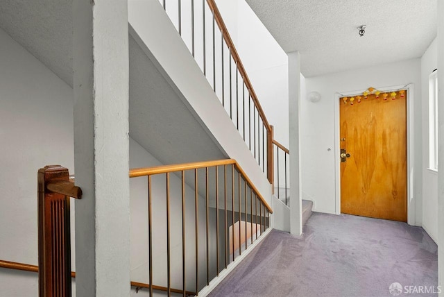 stairs featuring a textured ceiling and carpet flooring