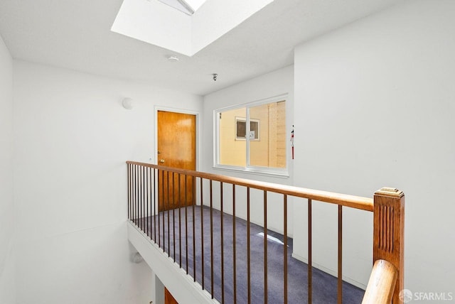 hall with a skylight and carpet flooring