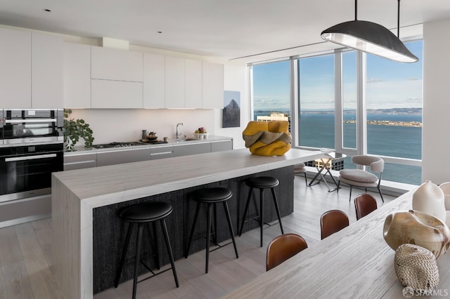 181 Fremont St Unit 62B, San Francisco, CA 94105 - kitchen featuring modern cabinets, a breakfast bar, light wood finished floors, expansive windows, and healthy amount of natural light