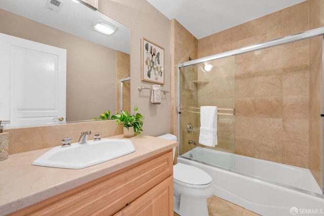 bathroom featuring tile patterned flooring, visible vents, toilet, combined bath / shower with glass door, and vanity