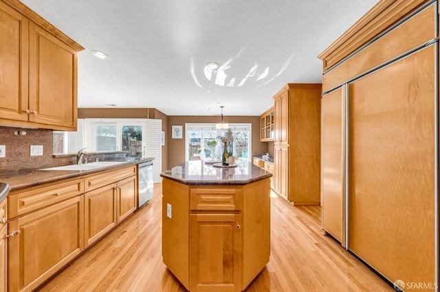 kitchen with tasteful backsplash, a center island, dishwasher, light wood-style floors, and a sink