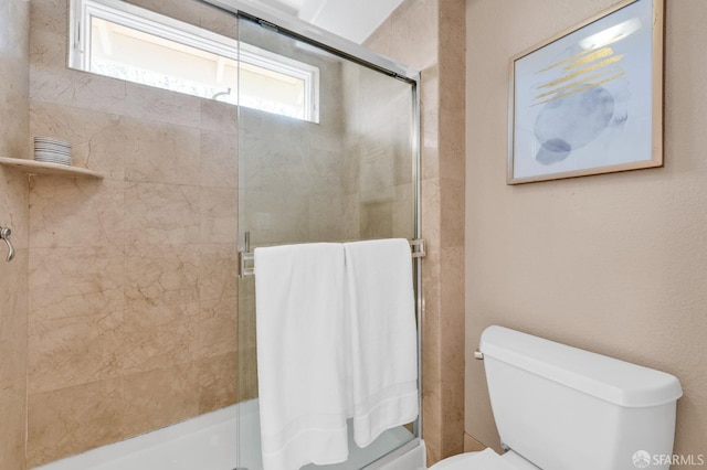 bathroom with a tile shower and toilet