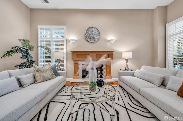 living room featuring a premium fireplace, plenty of natural light, baseboards, and wood finished floors