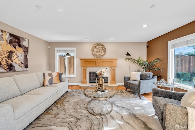 living room with a glass covered fireplace, recessed lighting, baseboards, and wood finished floors