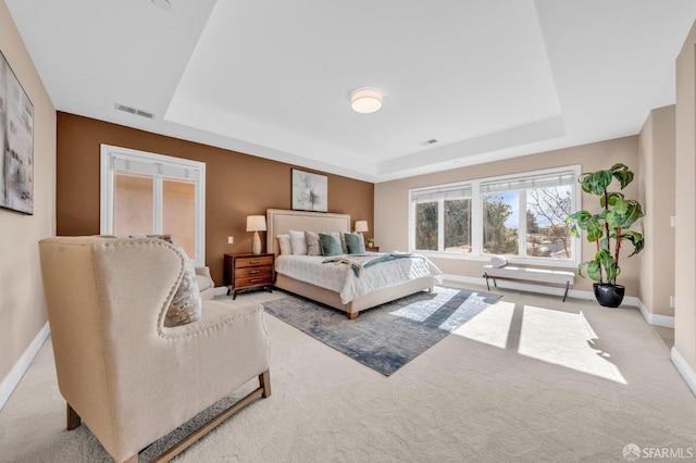 carpeted bedroom featuring a tray ceiling, baseboards, and visible vents