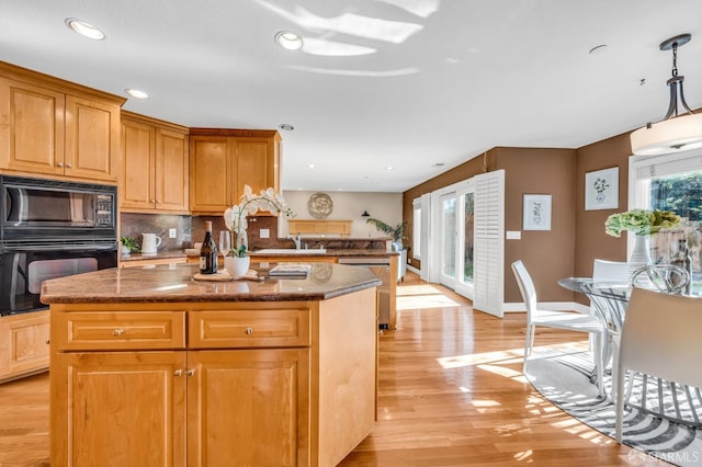 kitchen featuring recessed lighting, decorative backsplash, black appliances, light wood-type flooring, and a center island