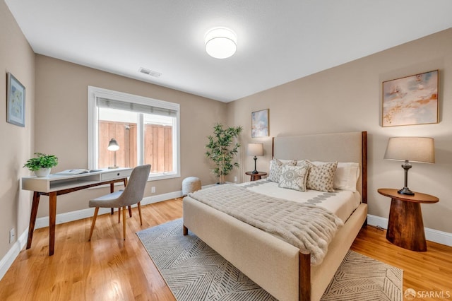 bedroom featuring visible vents, baseboards, and wood finished floors