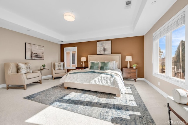 bedroom featuring a tray ceiling, baseboards, and light carpet