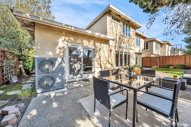 rear view of property with outdoor dining space, stucco siding, a patio, and fence