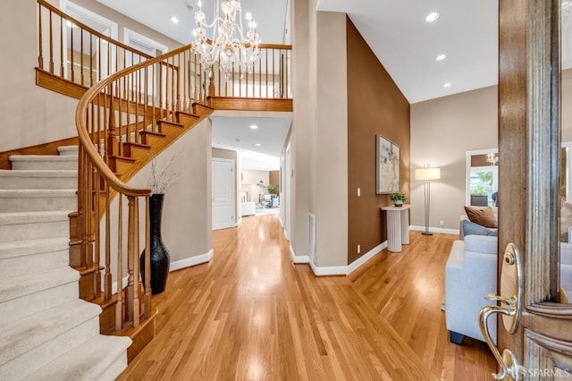 entryway featuring baseboards, stairway, recessed lighting, a towering ceiling, and wood finished floors