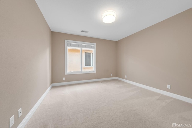 unfurnished room featuring visible vents, light colored carpet, and baseboards