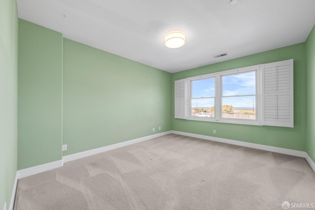 unfurnished room with visible vents, baseboards, and light carpet