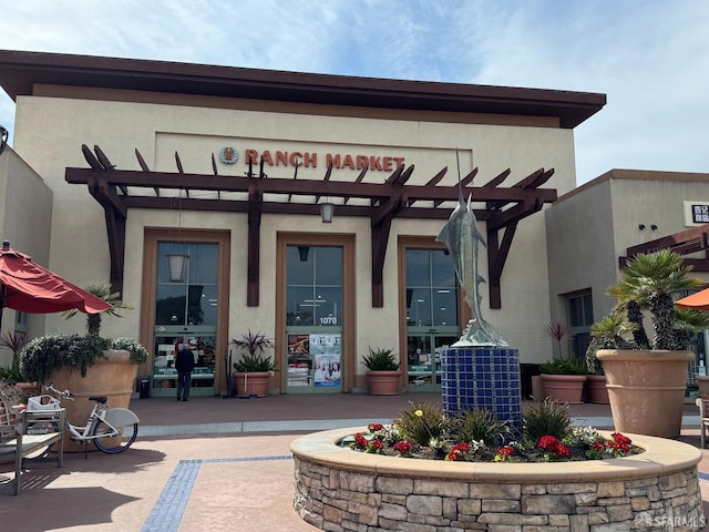 entrance to property featuring a pergola and stucco siding