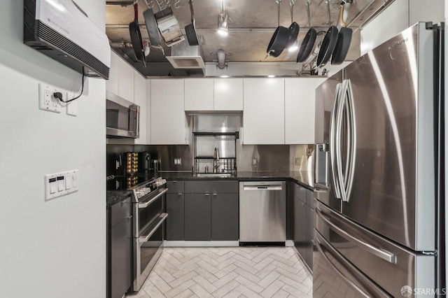 kitchen with white cabinetry, appliances with stainless steel finishes, sink, and dark stone countertops