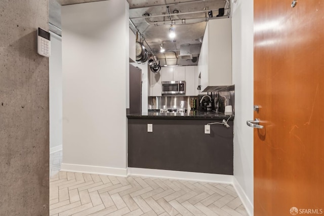 interior space with white cabinets, dark stone counters, and light parquet floors