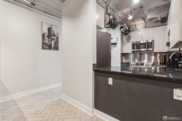 kitchen featuring sink, dark stone countertops, white cabinets, stainless steel appliances, and light parquet floors