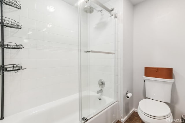 bathroom with toilet and shower / bath combination with glass door