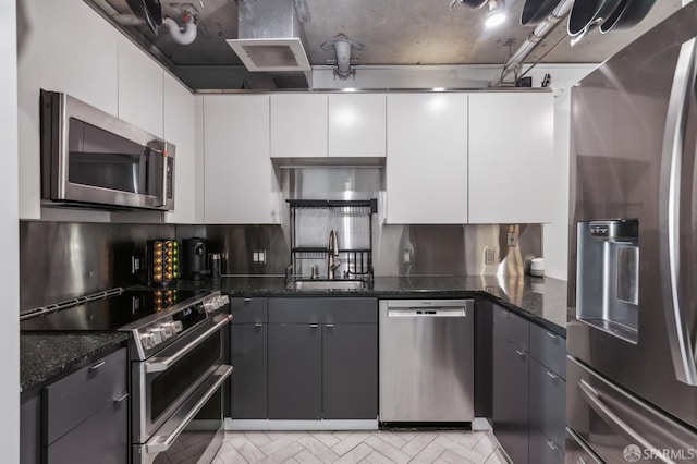 kitchen with sink, gray cabinets, appliances with stainless steel finishes, dark stone countertops, and white cabinets