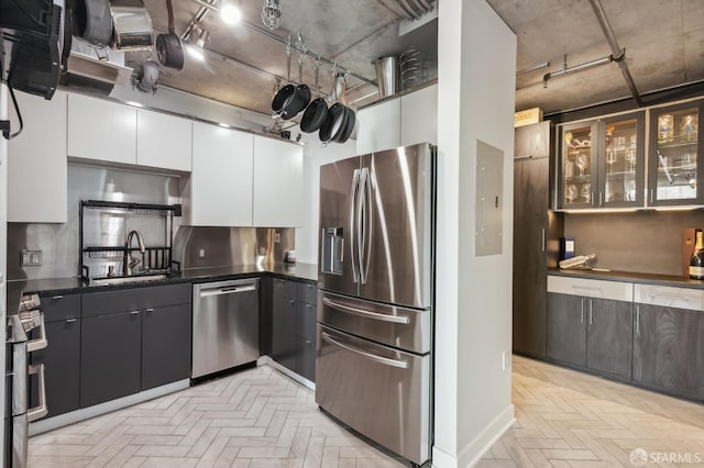 kitchen featuring appliances with stainless steel finishes, white cabinetry, sink, light parquet floors, and electric panel