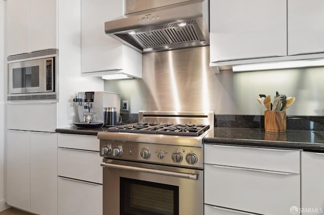 kitchen featuring white cabinets, appliances with stainless steel finishes, dark stone counters, and exhaust hood