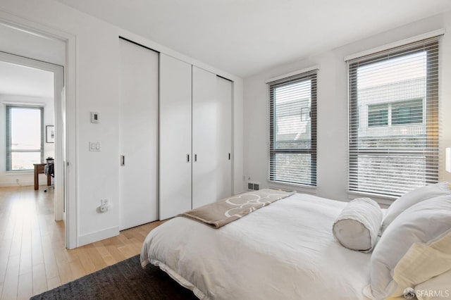 bedroom with multiple windows and light hardwood / wood-style flooring