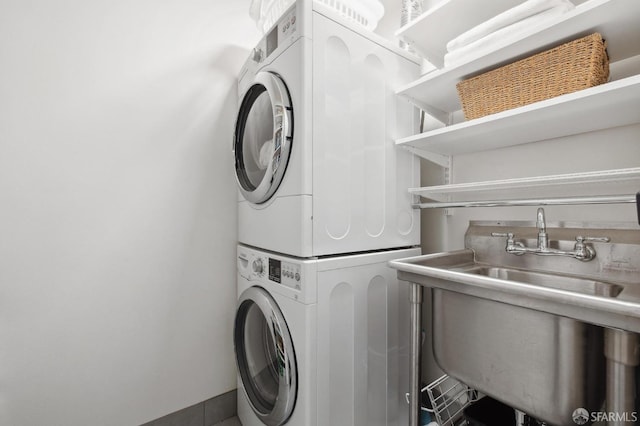 laundry area with stacked washer / drying machine and sink