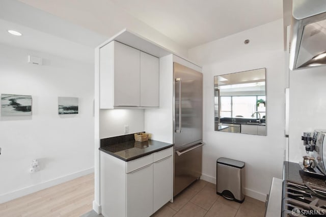 kitchen with white cabinetry, sink, and stainless steel built in refrigerator