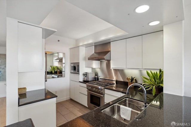 kitchen with white cabinets, wall chimney range hood, sink, light tile patterned floors, and appliances with stainless steel finishes