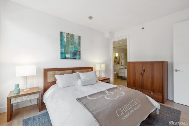 bedroom with hardwood / wood-style flooring and ensuite bath