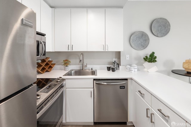 kitchen featuring appliances with stainless steel finishes, a sink, white cabinetry, and light countertops