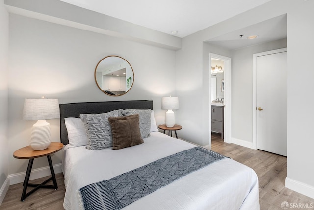 bedroom with wood finished floors, baseboards, and connected bathroom